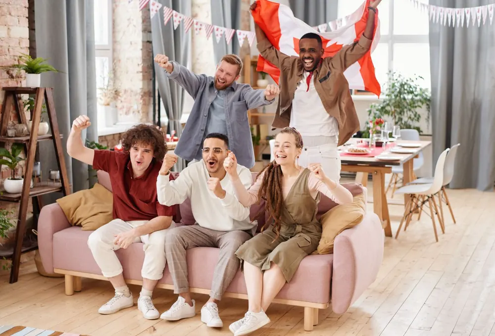 Friends cheering together under a Canadian flag